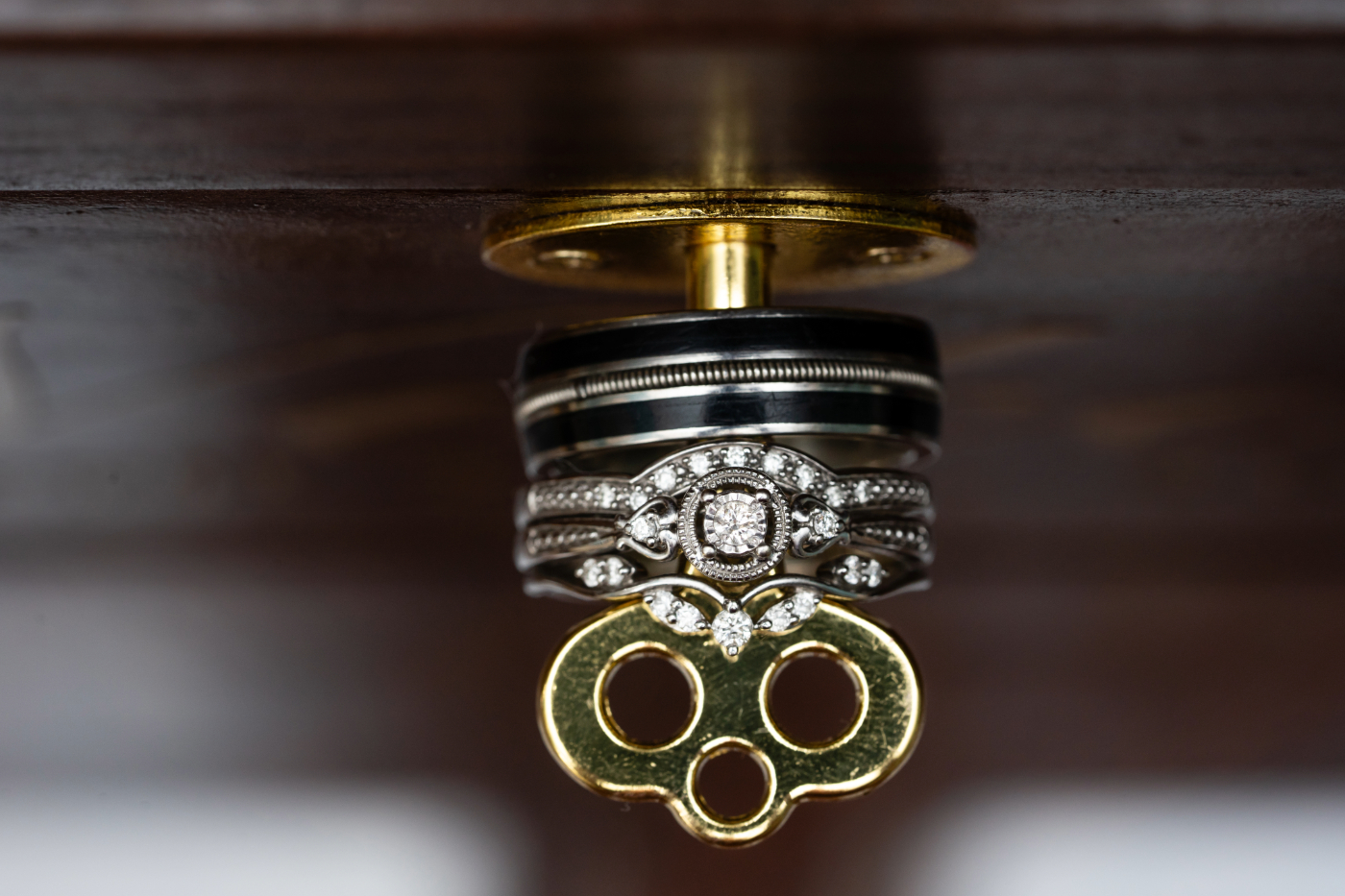 A set of wedding rings hang on a key in a wooden box, beautifully captured by an Oshkosh wedding photographer at the Gibson Social Club, Oshkosh.