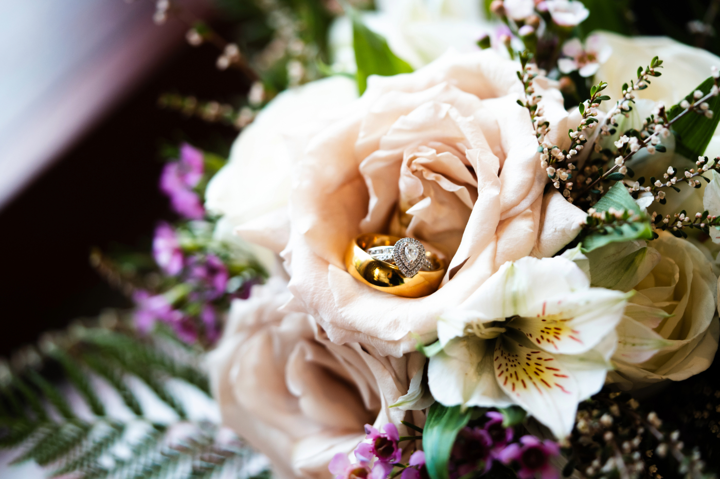 A detail image of wedding rings sitting in a flower of a bouquet from a Fox Valley, Wisconsin wedding photographer.